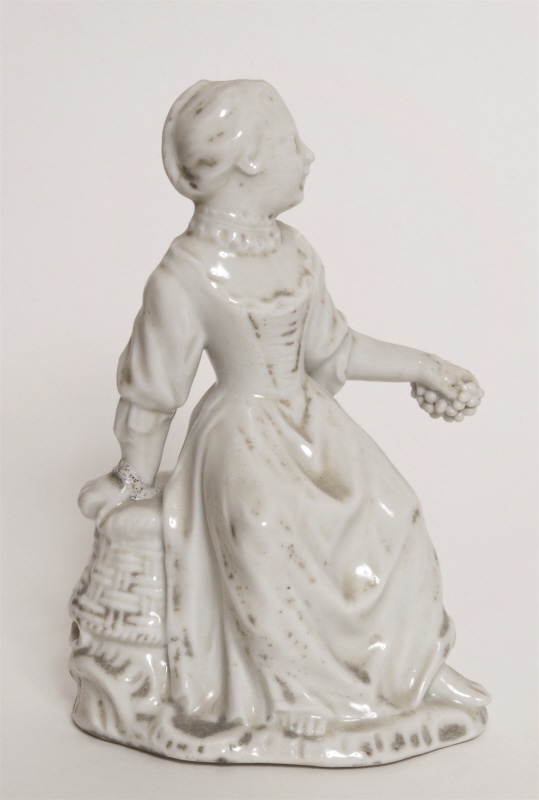 Figurin, flicka sittande på en kullstjälpt korg